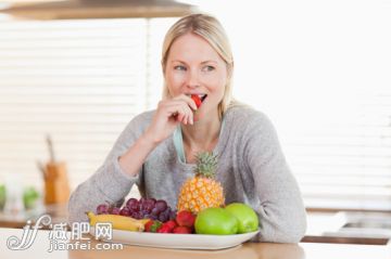 35岁到39岁,苹果,美女,早餐,瘦身_gic9736045_Woman sitting in the kitchen nibbling some fruits_创意图片_Getty Images China